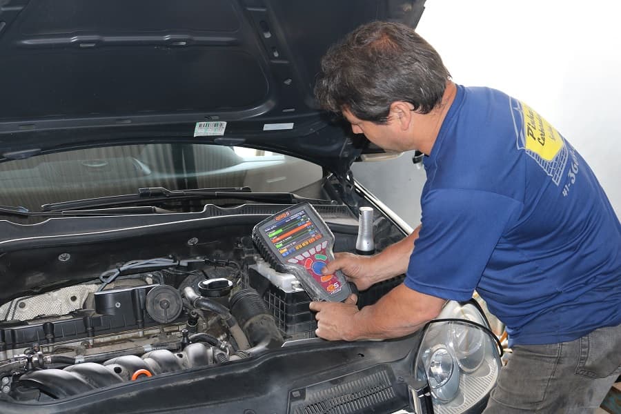 Mecânico com a camisa da Pinhais Carburadores usando scanner de diagnóstico no motor